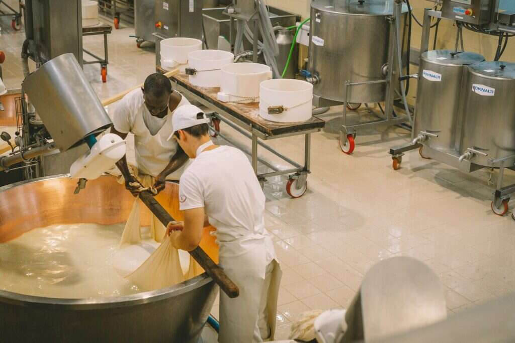 Casari al lavoro accanto alle caldaie di rame del caseificio